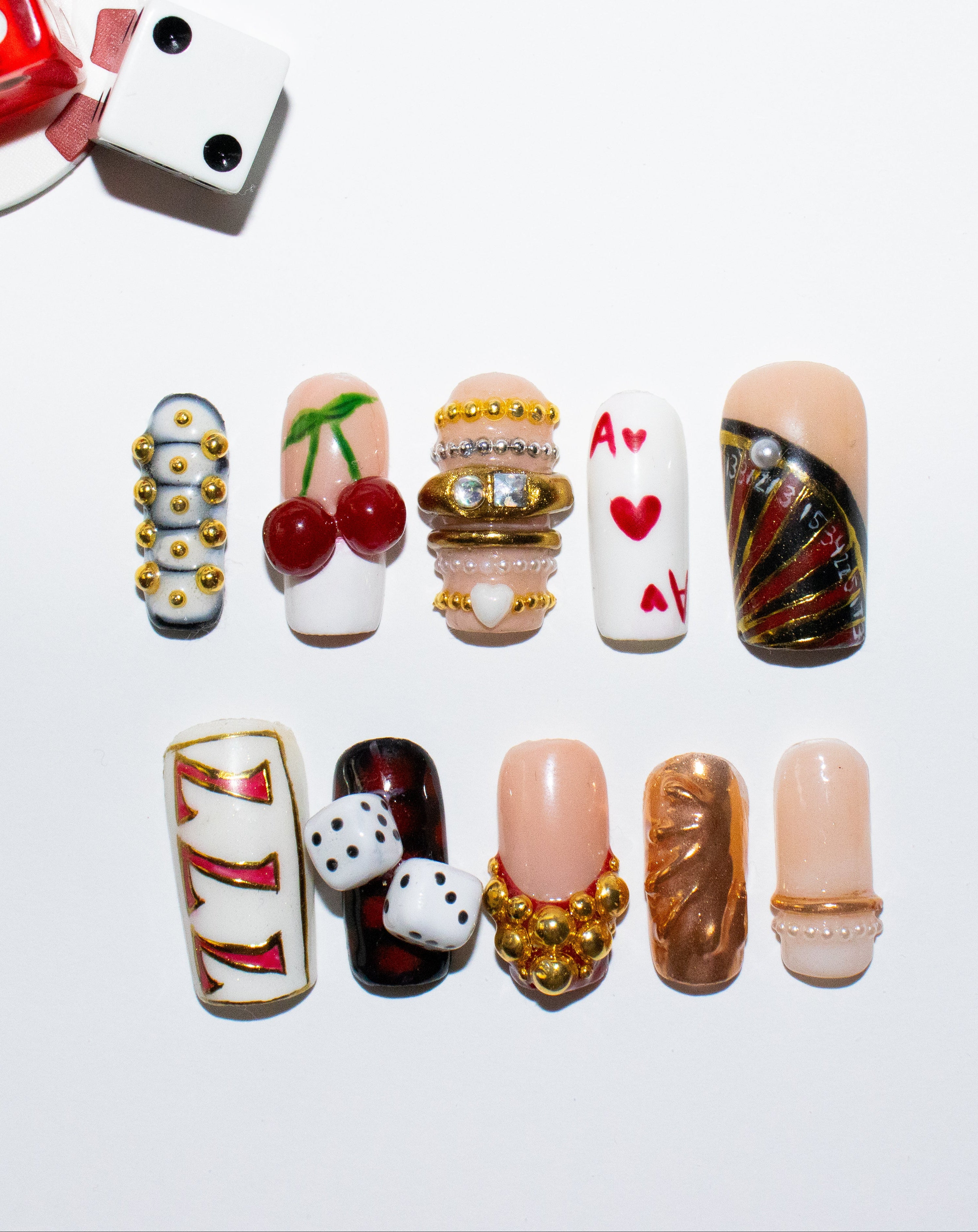 Decorative nail art designs on a white background with dice and a card.